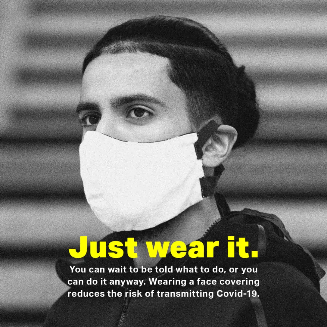 A social media advert showing a young man wearing a face covering looking off camera. The headline reads 'Just wear it.'