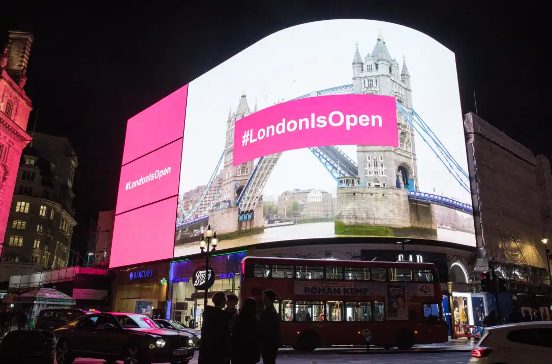 An ad spot in London's Piccadilly Lights of the campaign hashtag over an image of an open Tower Bridge