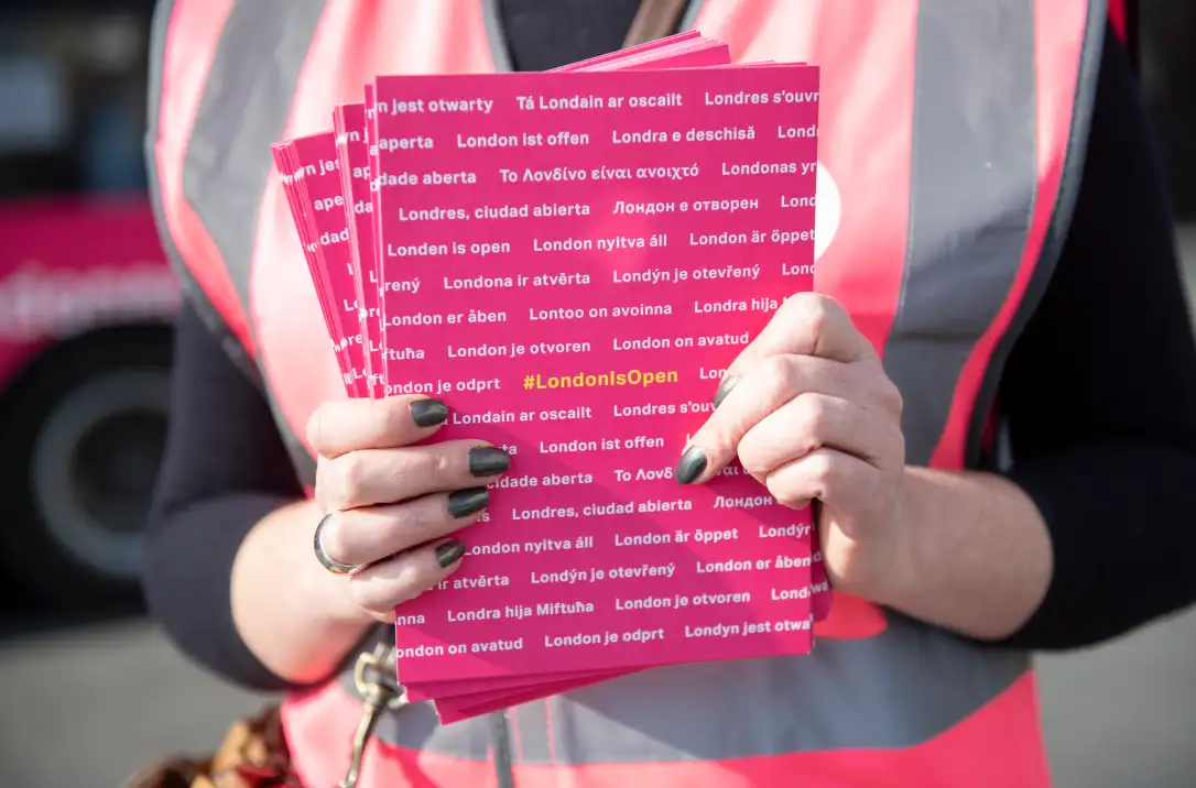 A close crop of a support worker holding a bunch of campaign leaflets